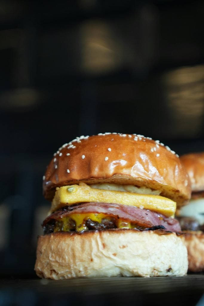 pexels-photo-33253853-33253853 Close-up of a delicious gourmet hamburger with a sesame seed bun, cheese, bacon, and pineapple.